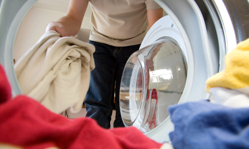 Man gooit kleding in wasmachine