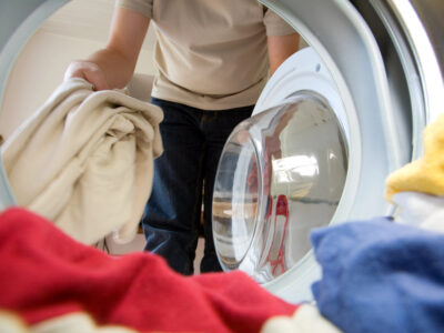 Man gooit kleding in wasmachine
